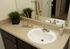 Elegant bathroom vanity with a sleek white sink, stylish chrome faucet, and decorative elements like plant and reed diffuser adding a touch of luxury.