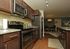 Modern kitchen with elegant dark wood cabinets, granite countertops, and stainless steel appliances leading into an inviting dining area.