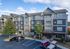 Charming four-story apartment building with modern siding and inviting entrance, surrounded by trees and spacious parking area.