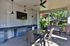 Stylish outdoor lounge area featuring a sleek dining set, wall-mounted TV, and lush garden views for perfect entertaining.