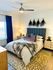 Chic bedroom with modern decor, featuring a cozy bed adorned with plush pillows and a faux fur throw, accented by elegant wall art and stylish bedside lighting.