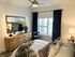 Chic bedroom with modern decor, featuring a wooden dresser, stylish artwork, and a cozy bed with plush pillows.
