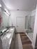 Elegant bathroom featuring a double vanity with sleek granite countertops, a modern glass-enclosed shower, and stylish wood flooring.