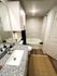 Modern bathroom featuring a sleek granite countertop, elegant fixtures, and a luxurious tiled bathtub.