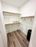 Spacious walk-in closet with elegant wood flooring and ample shelving, perfect for organized living.