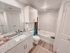 Elegant bathroom with modern fixtures, granite countertop, spacious mirror, and marble-tiled bathtub.