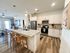 Modern open-concept kitchen with sleek countertops, stainless steel appliances, and stylish bar seating adjacent to a cozy living area.