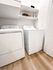 Modern laundry room with sleek white washer and dryer, complemented by wooden flooring and efficient storage shelves.