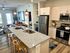 Modern open-concept apartment with elegant kitchen, sleek stainless steel appliances, inviting living area, and stylish bar seating.