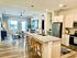 Modern open-concept apartment kitchen with marble countertops, stylish barstools, and a cozy living area bathed in natural light.