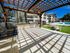 Charming outdoor BBQ area with pergola shade, sleek grills, and a view of the luxurious apartment complex and sparkling swimming pool.
