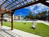 Inviting outdoor space featuring a pergola, lush green lawn, and luxurious pool with stylish seating area.