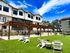 Inviting outdoor space with a modern pergola, cozy seating, and vibrant green lawn, perfect for relaxation and entertaining.