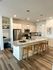 Modern kitchen with sleek granite countertops, stainless steel appliances, and elegant pendant lighting, complemented by stylish wooden bar stools on warm wood flooring.
