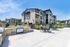 Inviting apartment complex with modern stone facade, outdoor seating, and a grill area, perfect for relaxation and social gatherings.