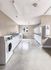 Modern laundry room featuring rows of pristine white washing machines and dryers with ample natural light.