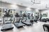 Modern fitness center featuring state-of-the-art treadmills and exercise bikes, with large windows offering a scenic view of the outdoor pool area.
