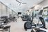 Modern fitness center with state-of-the-art equipment, featuring treadmills, ellipticals, and a weight training area, bathed in natural light.