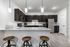 Modern kitchen with sleek dark cabinets, granite countertops, stainless steel appliances, and stylish pendant lighting over a breakfast bar with wooden stools.