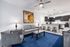 Contemporary living room with elegant gray sofas, modern art, and a spacious open-concept kitchen featuring sleek dark cabinets and stylish bar seating.