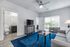 Bright and modern living room featuring sleek gray furniture, a striking blue rug, and natural light pouring through sliding doors.