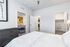 Bright and inviting bedroom with cozy bedding, modern dresser, spacious walk-in closet, and a glimpse into the stylish living room with contemporary decor.
