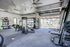 Modern apartment gym with premium exercise equipment, featuring floor-to-ceiling windows and sleek finishes.