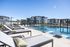 Luxurious apartment complex featuring a modern swimming pool area with stylish lounge chairs and elegant poolside amenities, set against contemporary architecture.