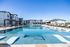 Luxurious apartment complex featuring a stunning resort-style pool with modern lounge chairs and picturesque surroundings.