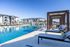 Luxurious apartment complex showcasing a pristine swimming pool with modern lounge areas and stylish pergolas under a clear blue sky.