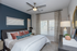 Modern bedroom with elegant decor, featuring a cozy bed with plush pillows, stylish lamp, and contemporary artwork.