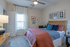 Inviting bedroom with modern decor, featuring a cozy bed with colorful pillows, framed art, and elegant lighting.