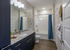 Contemporary bathroom with elegant granite countertop, stylish dark cabinetry, and a chic shower with blue curtain.