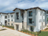 Modern apartment complex featuring sleek architectural design with stone and panel detailing, offering spacious balconies and well-maintained outdoor spaces.
