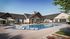 Luxurious community pool area featuring stylish loungers, shaded seating, and a modern clubhouse under a clear blue sky.
