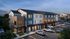 Modern multi-level apartment complex with sleek architecture, abundant windows, and ample parking spaces, set in a serene neighborhood at dusk.