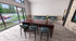 Modern and inviting dining area with floor-to-ceiling windows, stylish wooden table, and vibrant seating, offering a bright and open atmosphere.