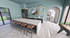 Modern open kitchen with a long island, sleek appliances, and vibrant geometric backsplash, leading to a sunlit archway.