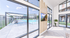 Chic apartment interior with large windows overlooking a sunlit outdoor pool area, complete with lounge chairs and modern amenities.