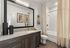 Elegant modern bathroom featuring a granite countertop, sleek vanity, large mirror, and luxurious bathtub with marble surround.