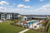 Chic apartment complex featuring a luxurious pool area with sun loungers, modern outdoor seating, and lush green lawns under a vibrant blue sky.