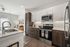 Modern open-concept kitchen and living area featuring sleek stainless steel appliances, granite countertops, and a cozy seating space with stylish decor.
