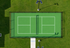 Vibrant green tennis court surrounded by lush grass, featuring solar-powered lighting for day and night play.