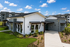 Modern duplex building with sleek design, featuring manicured landscaping and a bright entrance under a blue sky.