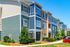 Charming and colorful three-story apartment complex with vibrant siding and lush landscaping under a clear blue sky.