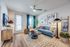 Inviting living room with modern d&eacute;cor, featuring a plush blue sofa, abstract artwork, and a chic marble coffee table, bathed in natural light.