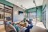 Modern living area with sleek decor, stylish seating, large TV, and abundant natural light, perfect for relaxation and entertainment.