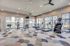 Modern fitness center with large windows, state-of-the-art treadmills, and diverse exercise equipment featuring a colorful carpet design.