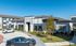 Modern apartment complex with sleek exteriors, landscaped surroundings, and ample parking space.