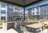 Chic outdoor space featuring a modern grill and dining area, set against a backdrop of stylish apartment buildings.